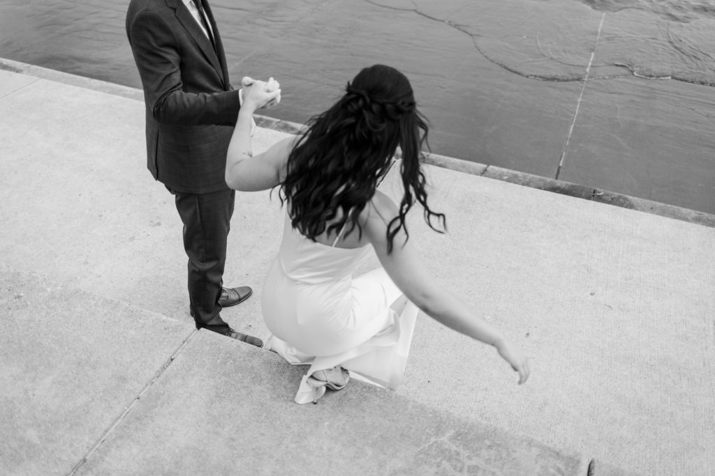 Groom helping his bride down some steps near the Chicago lakefront