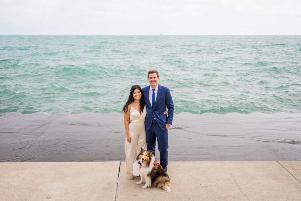 Couple smiling with their dog in front of Lake Michigan after their elopement in Chicago