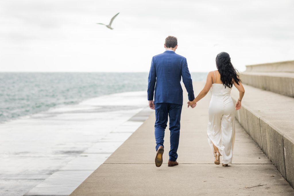 Bride and groom walking hand in hand down the lakefront trail in Chicago