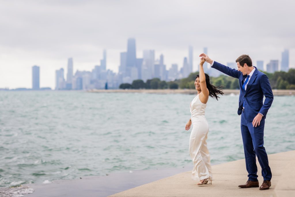 Groom spinning bride while she smiles with the Chicago skyline in the background