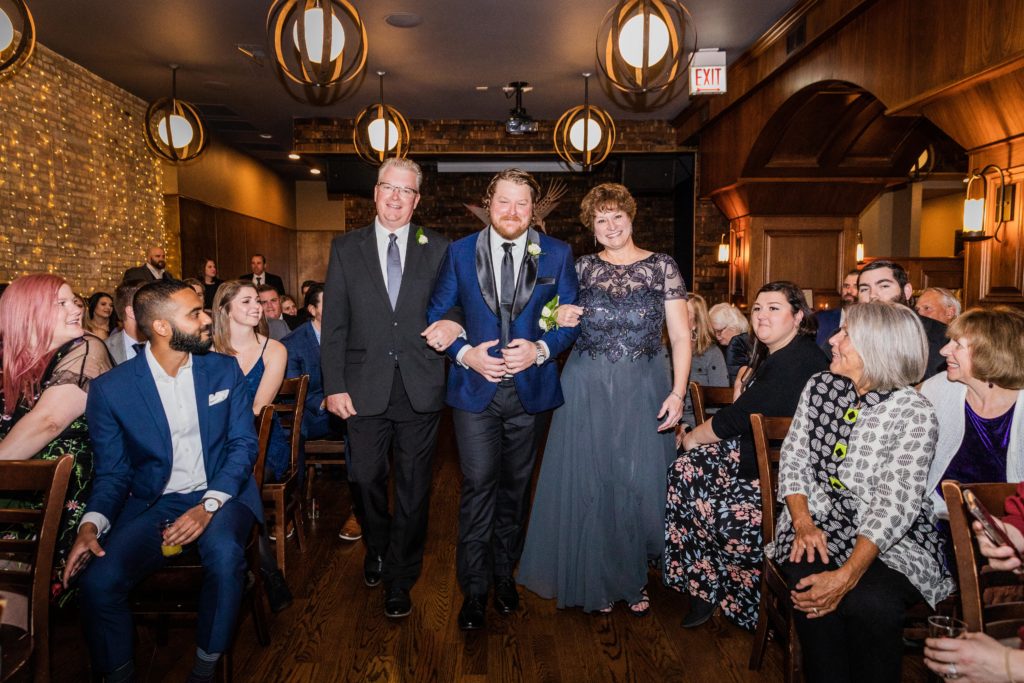 Groom walks down the aisle with his parents at a Revolution Brewing Wedding
