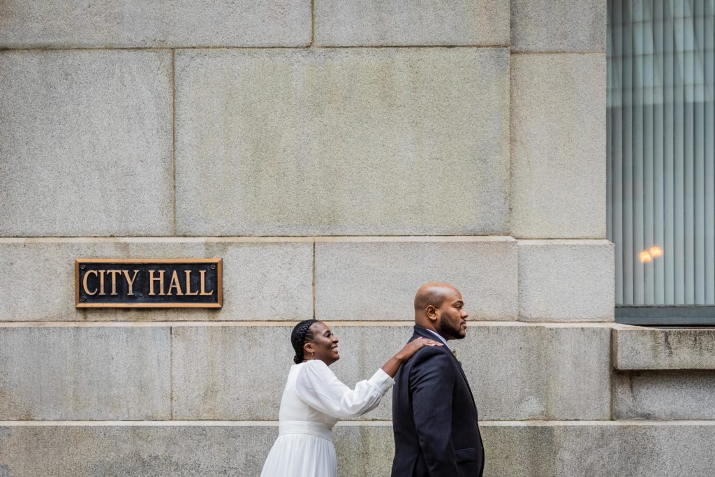 Bride touches groom's shoulder before he sees her before their Chicago city hall wedding