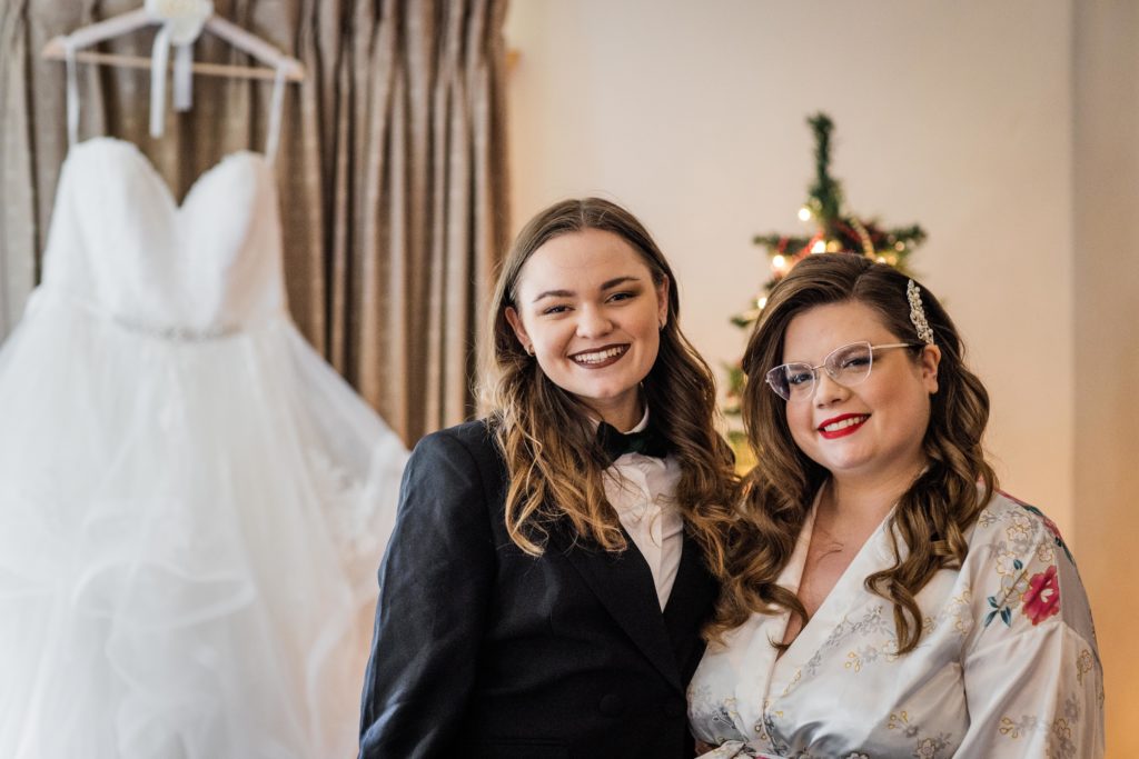 Bride poses with her step daughter in front of her wedding dress