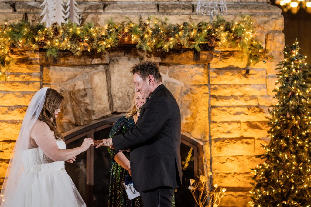 Groom places ring on bride's hand during their wedding at Starved Rock