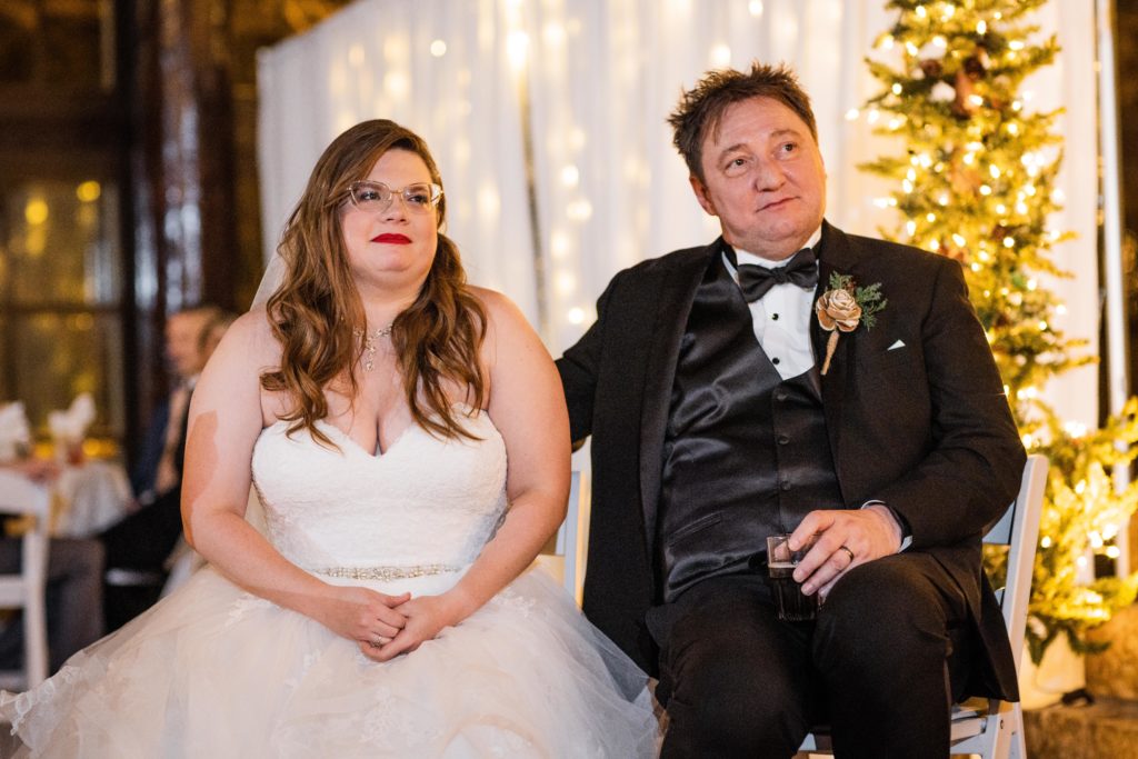 Bride and groom listen to reception speeches