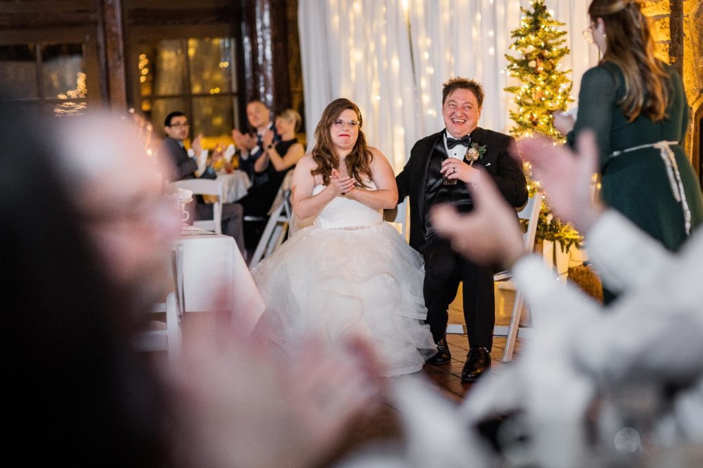 Bride and groom clap after hearing the maid of honor give a speech