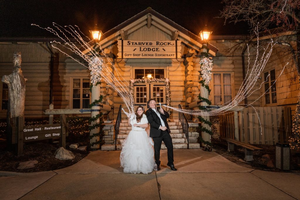 Bride and groom shoot out streamers in front of the Starved Rock Lodge