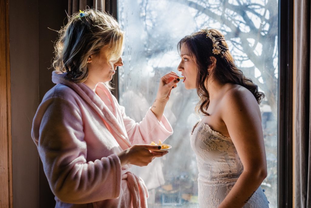 Bride being fed french fries by the Maid of honor
