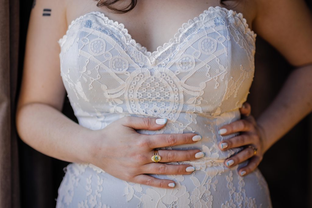 Bride holds her torso and shows off her nails and rings