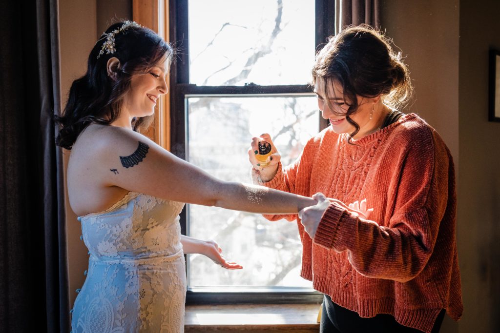 bridesmaid helping the bride put on perfume