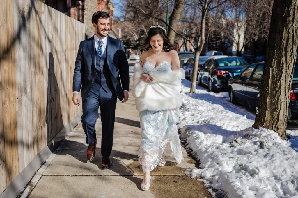 bride and groom walk down the street in winter before their wedding at Ovation Chicago
