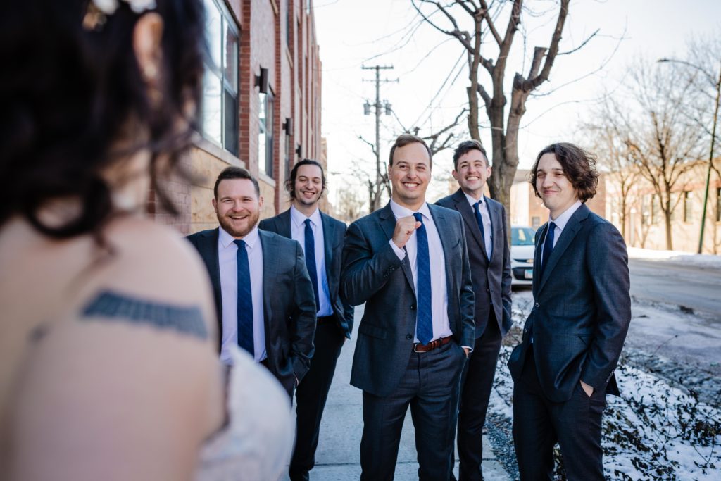 Groomsmen smile while seeing the bride for the first time