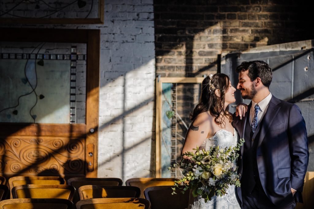 Bride and groom look at each other in the window light at Salvage One