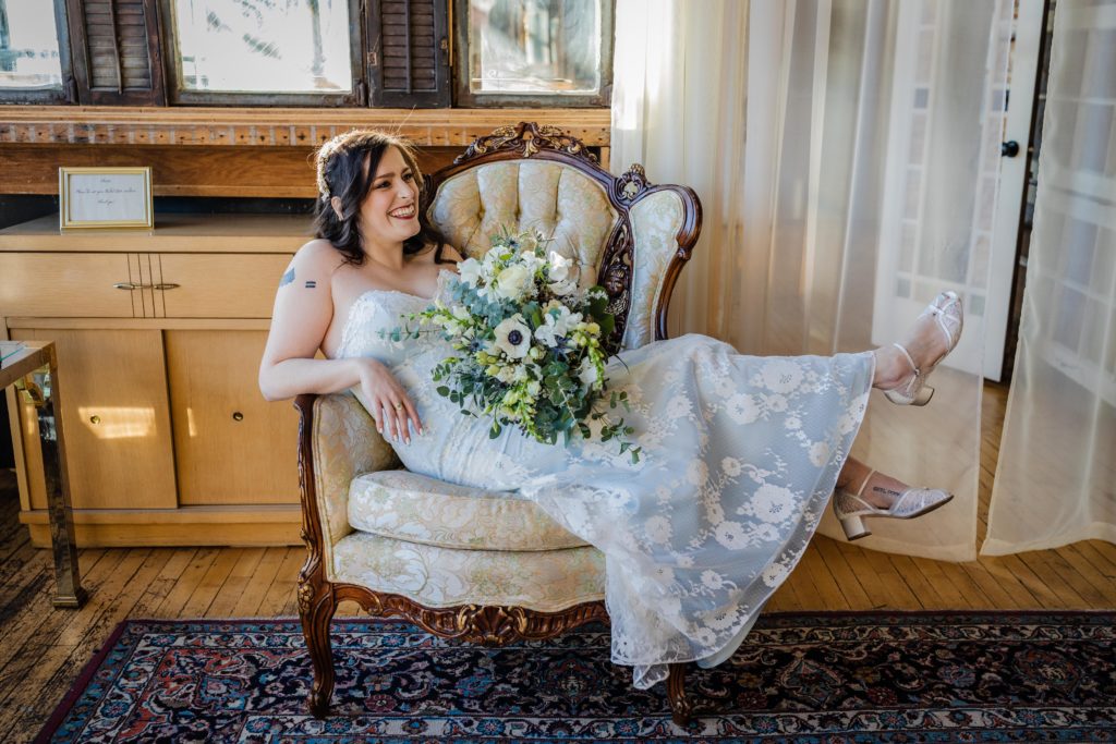 Bride smiles as she lounges in a vintage chair