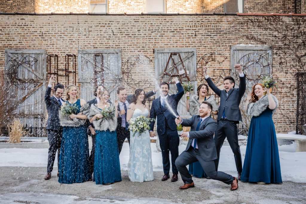 Groomsman sprays champagne in the Salvage One courtyard 