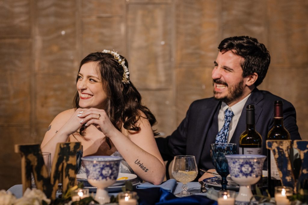 Couples laughs while sitting at their table and listening to a speech at Ovation Chicago