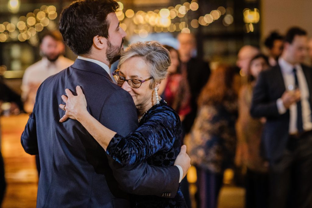 Groom's mom buries her head in his shoulder during their first dance at Ovation Chicago