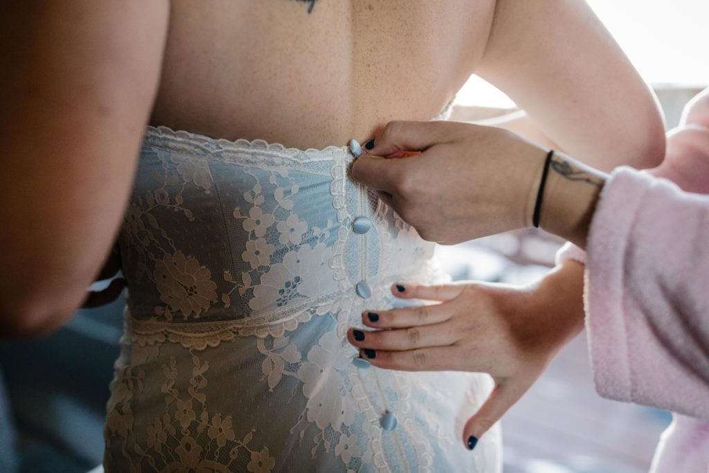 Maid of honor zipping up the back of the bride's dress