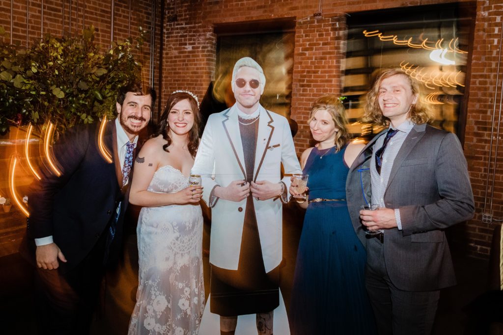 bride and groom pose with friends and a cardboard cutout of pete davidson at Ovation Chicago