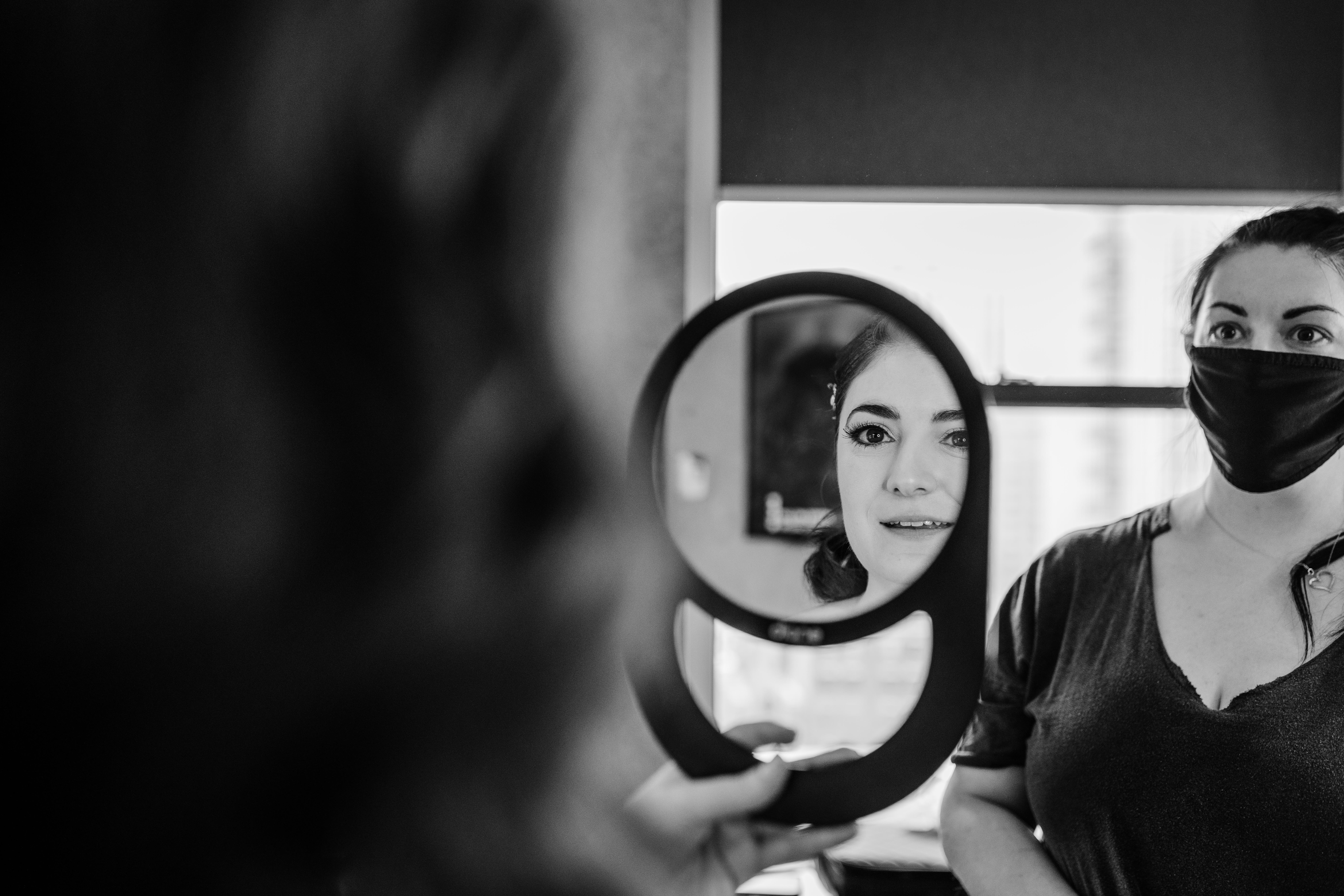 Bride looking at her reflection in a hand mirror at the Clardige house before her Revolution Brewing Wedding