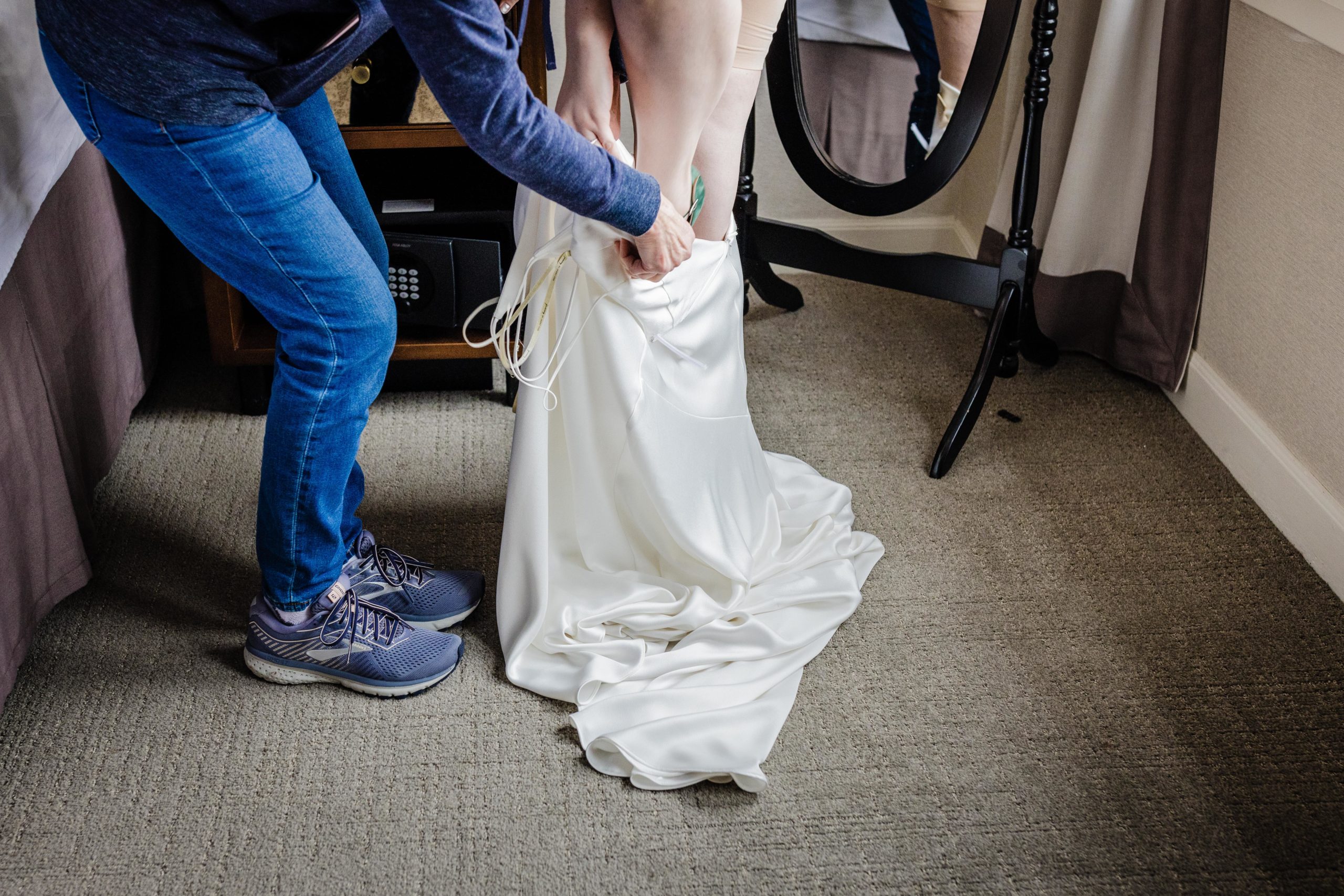 Bride putting on her dress with the help of her mom