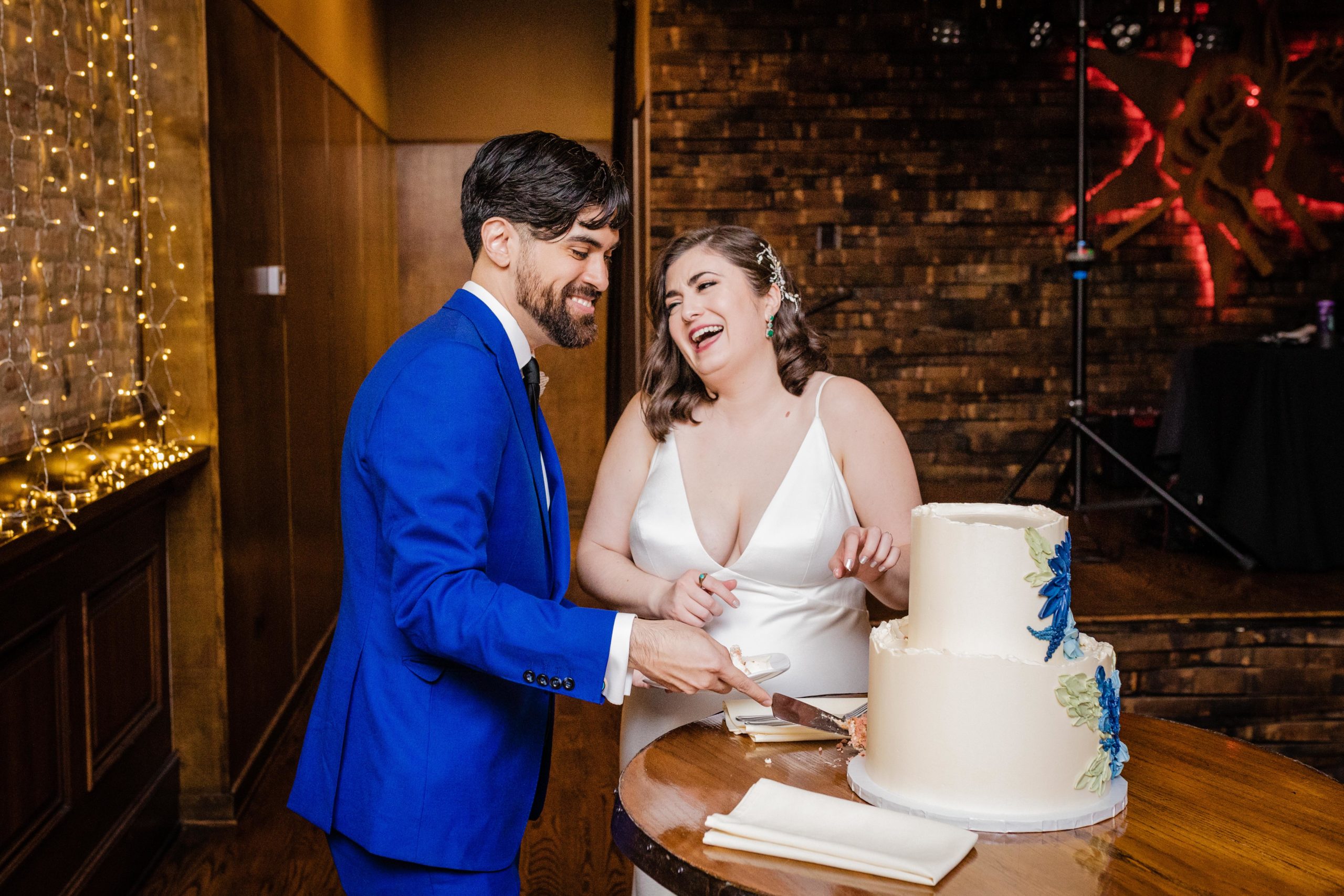 Bride and groom laughing while cutting the cake at their Revolution Brewing Wedding