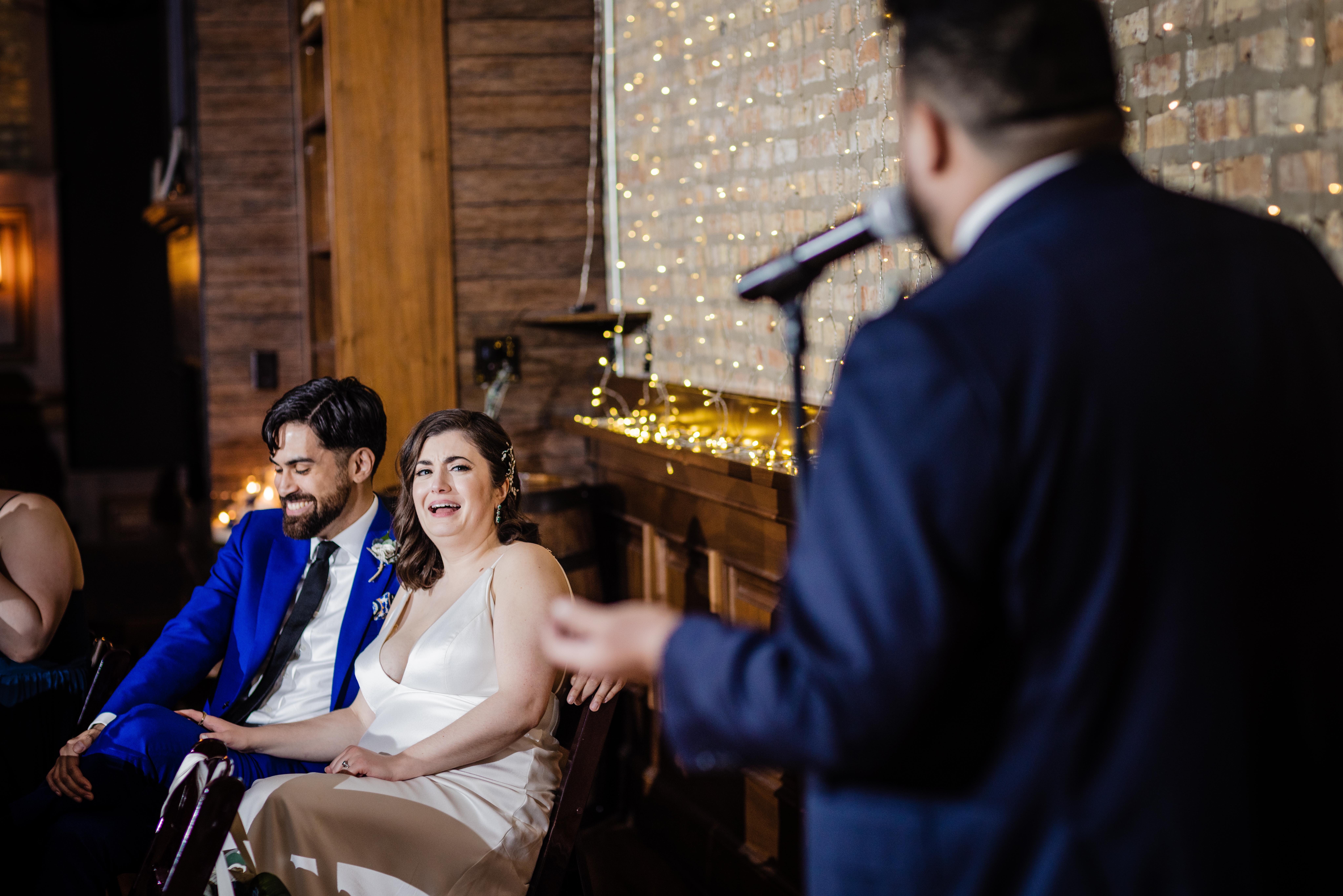 Couple laughing at the best man giving a speech at their Revolution Brewing Wedding