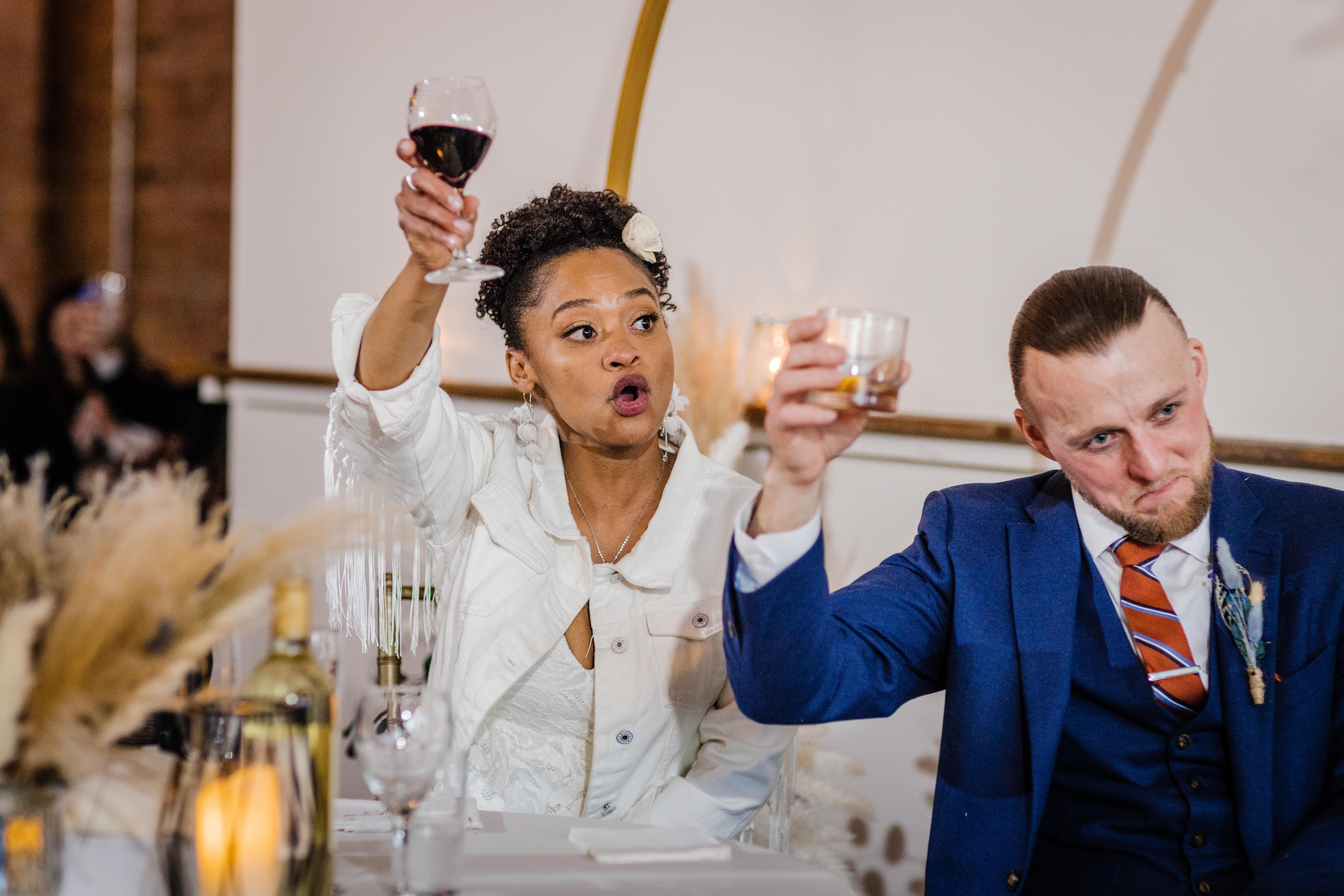 Couple lift up glasses to toast the speaker at their Bottom Lounge Wedding