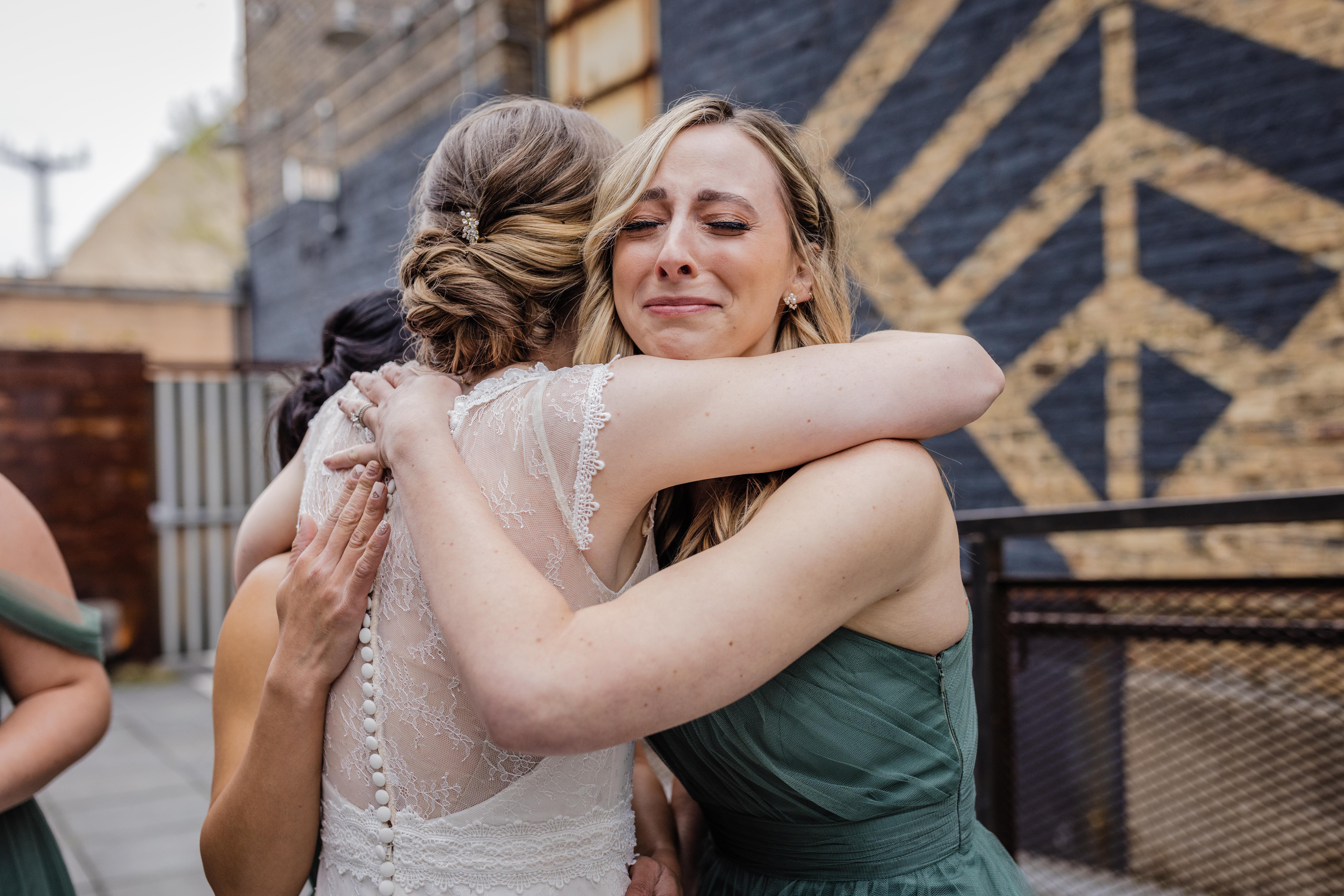 bridesmaid crying while hugging the bride at the joinery