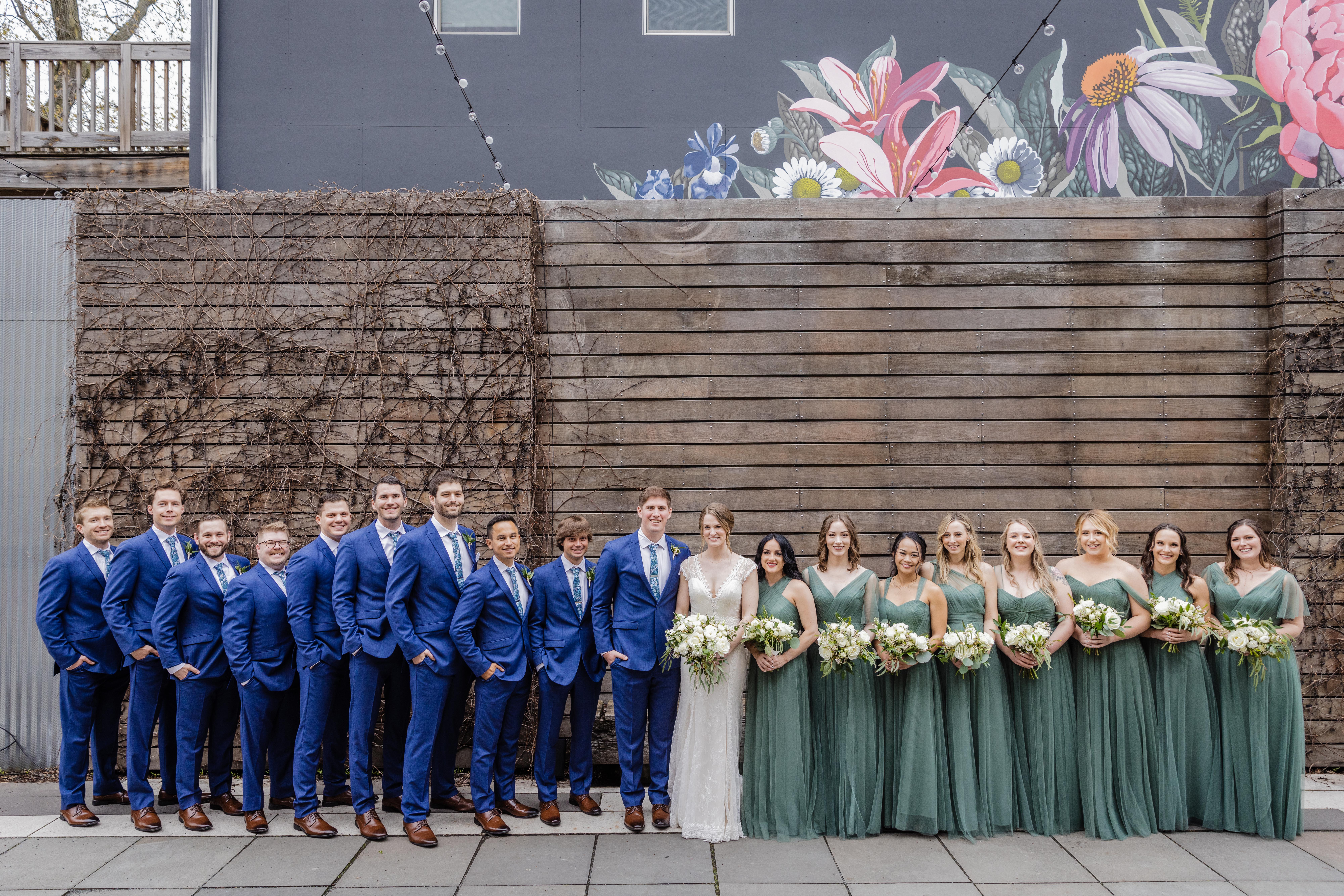Full wedding party standing together in the joinery courtyard