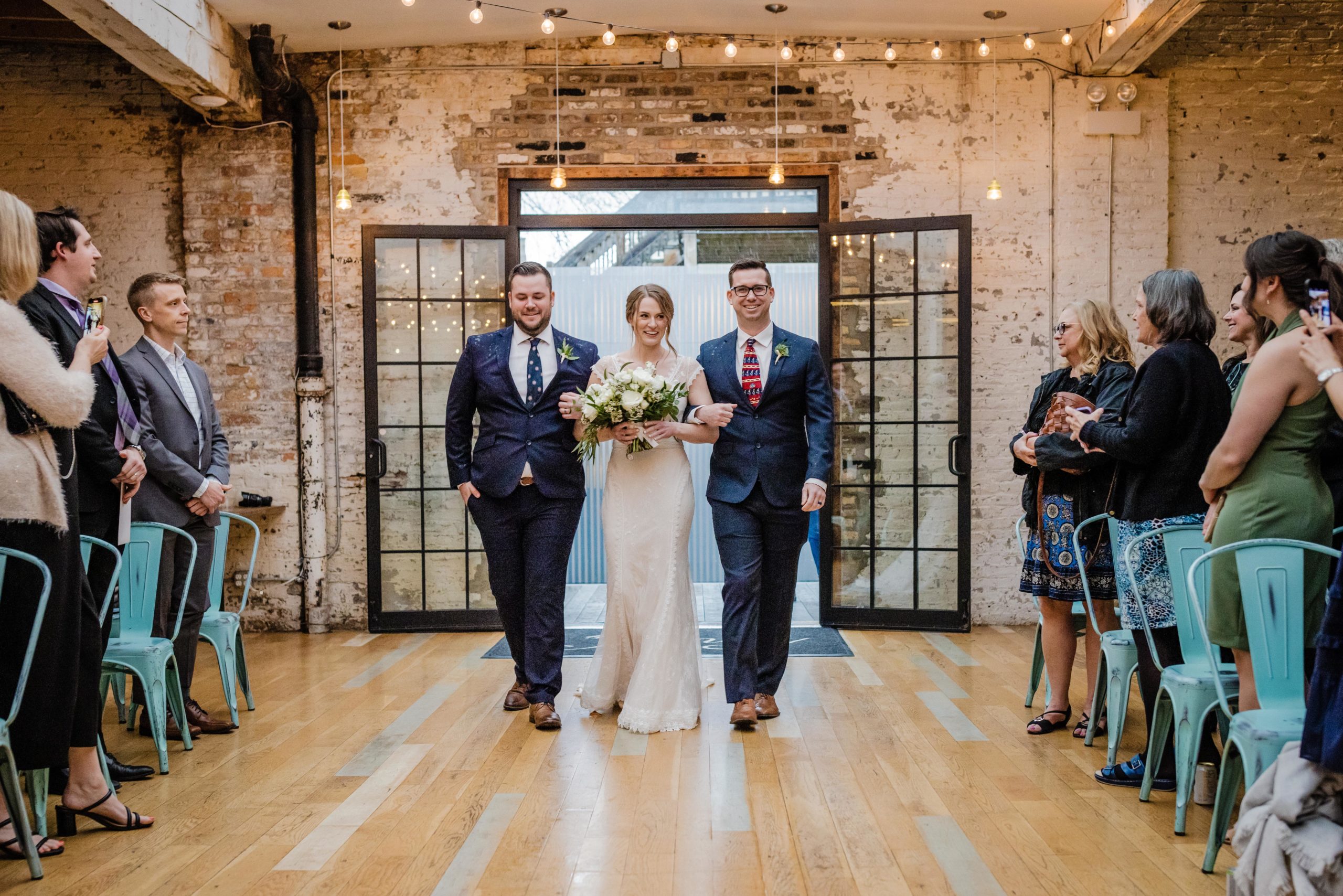 Bride being walked down the aisle by her brothers at The Joinery